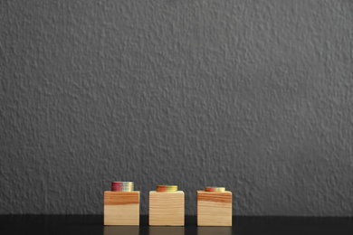 Photo of Wooden blocks with space for text and coins on table. Tax concept