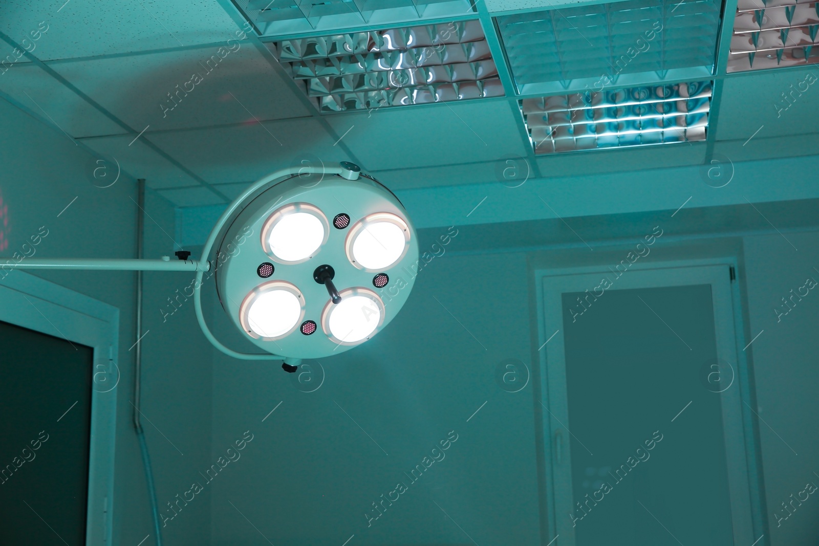 Photo of Powerful surgical lamps in dark operating room. Space for text