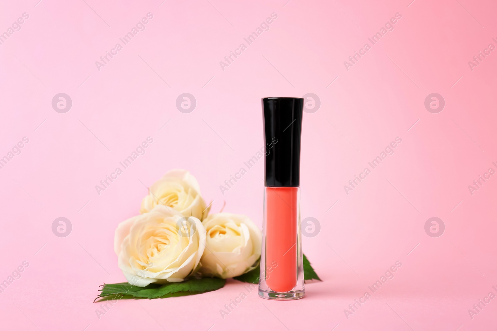 Photo of Lip gloss and flowers on color background