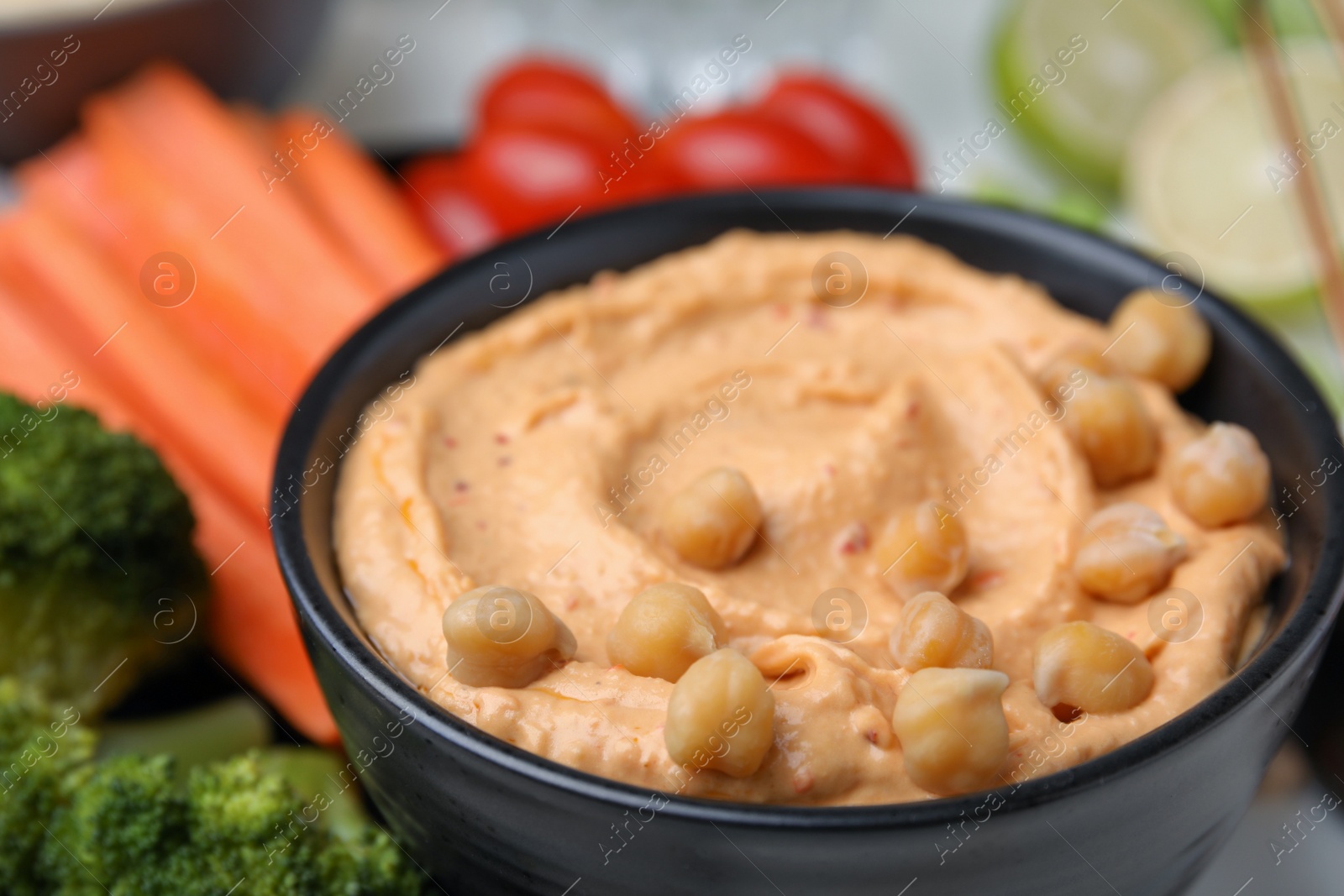 Photo of Bowl with delicious hummus and fresh vegetables, closeup