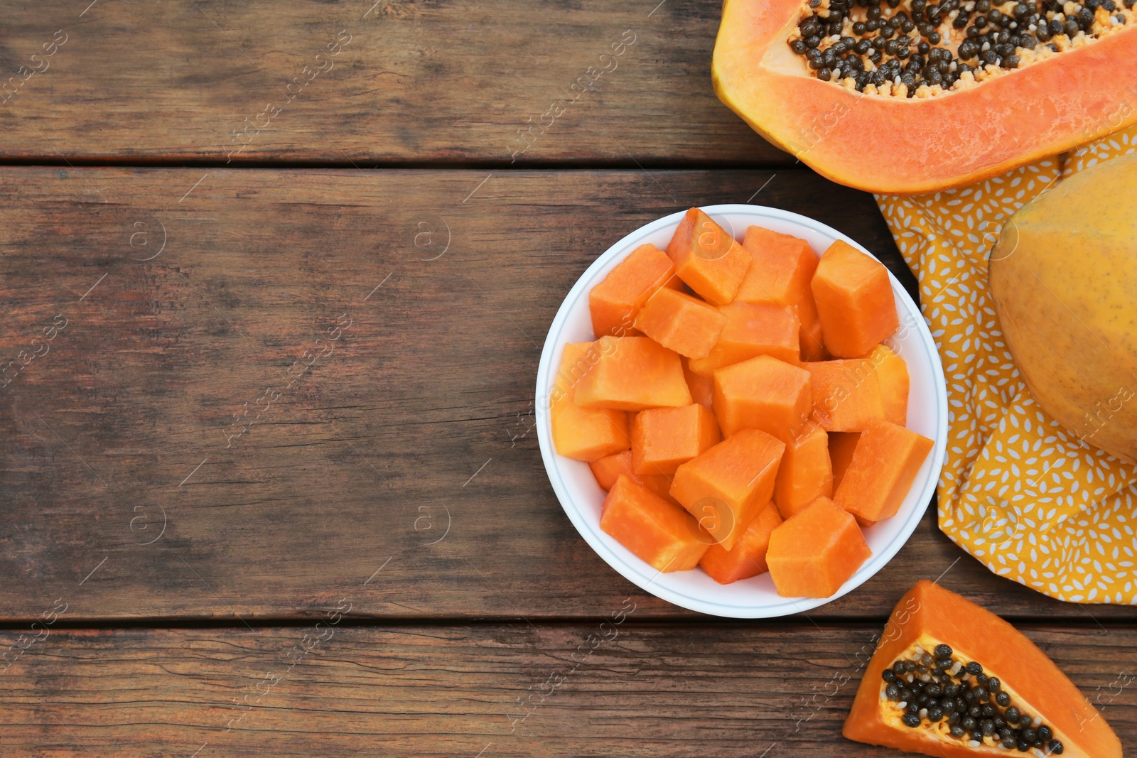 Photo of Tasty whole and cut papaya fruits on wooden table, flat lay. Space for text