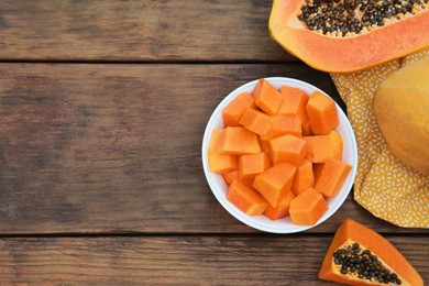 Photo of Tasty whole and cut papaya fruits on wooden table, flat lay. Space for text