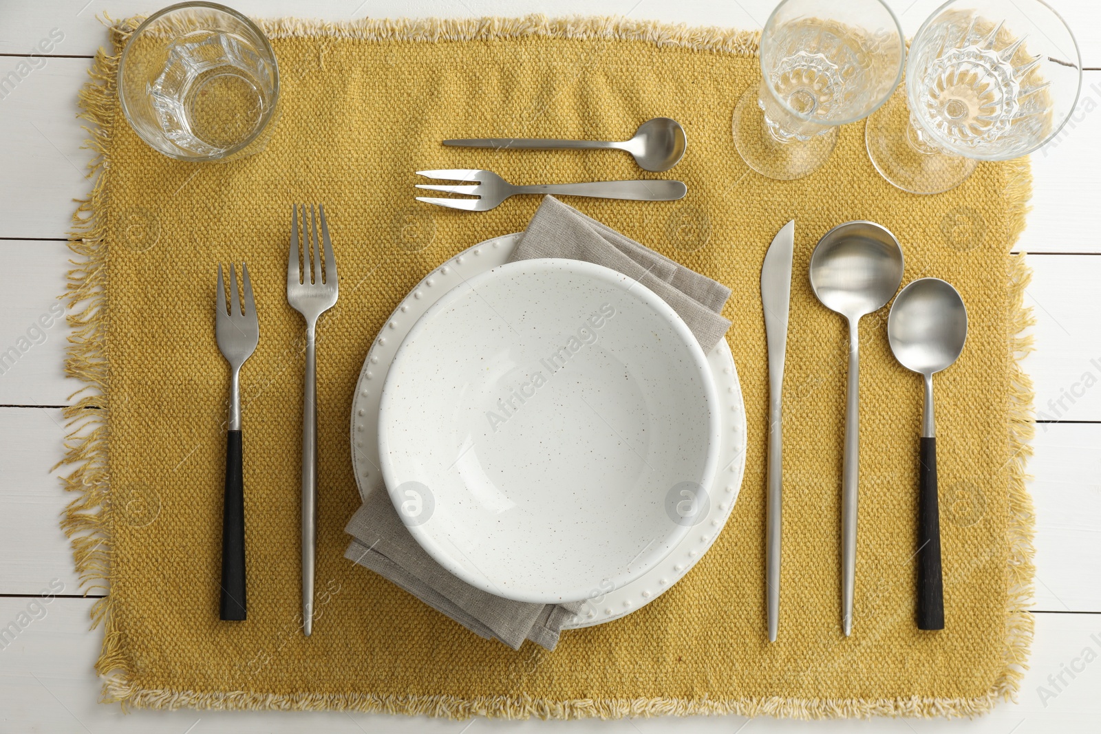 Photo of Stylish setting with cutlery, dishes, glasses and napkin on white wooden table, top view