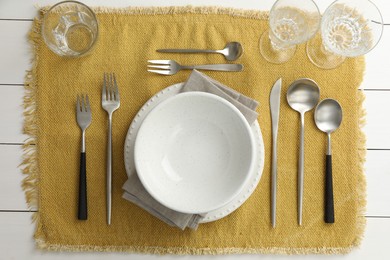 Stylish setting with cutlery, dishes, glasses and napkin on white wooden table, top view