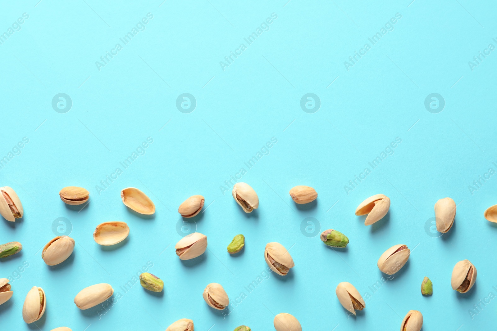 Photo of Composition with organic pistachio nuts on color background, flat lay. Space for text