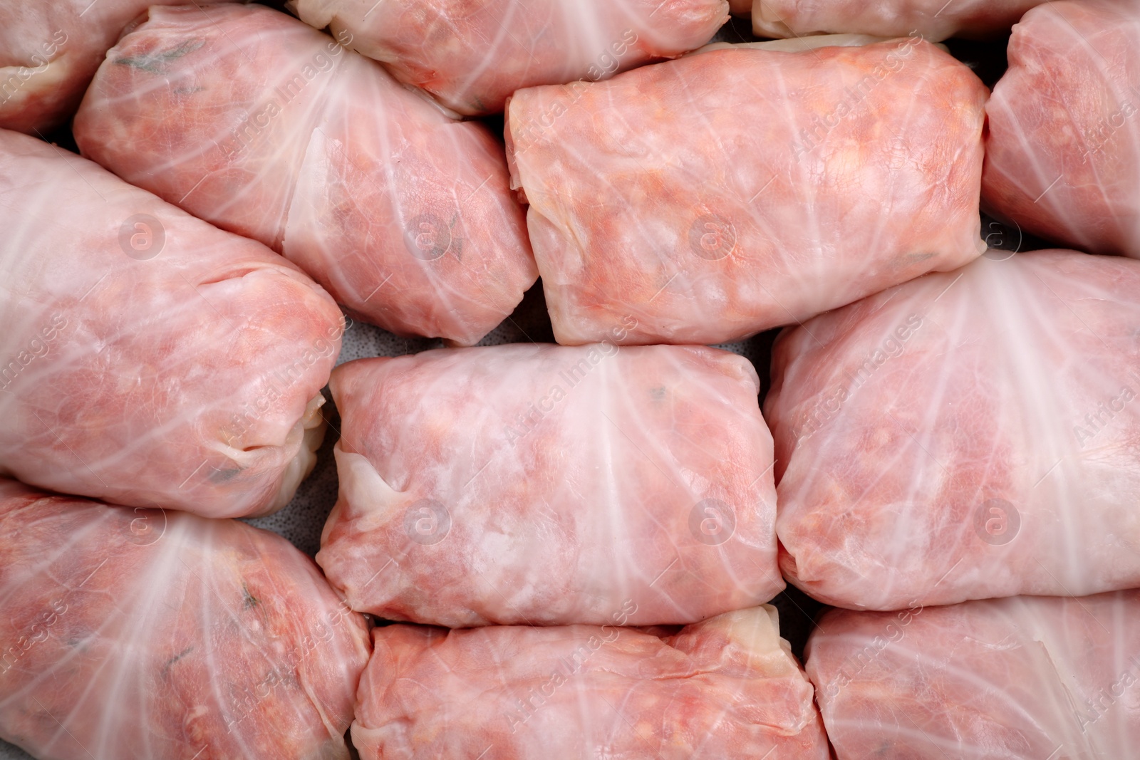 Photo of Uncooked stuffed cabbage rolls on plate, top view