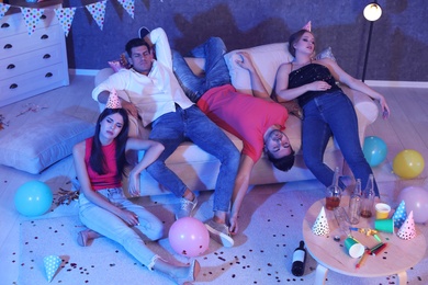 Photo of Group of friends sleeping in messy room after party at night