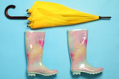 Photo of Flat lay composition with umbrella and rubber boots on color background