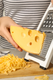 Photo of Woman grating fresh cheese at table, closeup