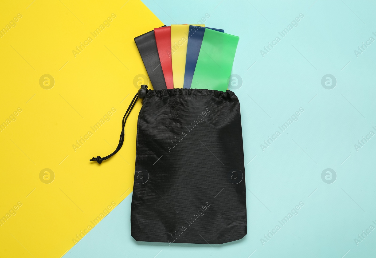 Photo of Bag with fitness elastic bands on color background, top view