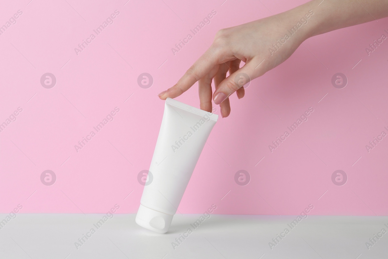 Photo of Woman with tube of cream on color background, closeup