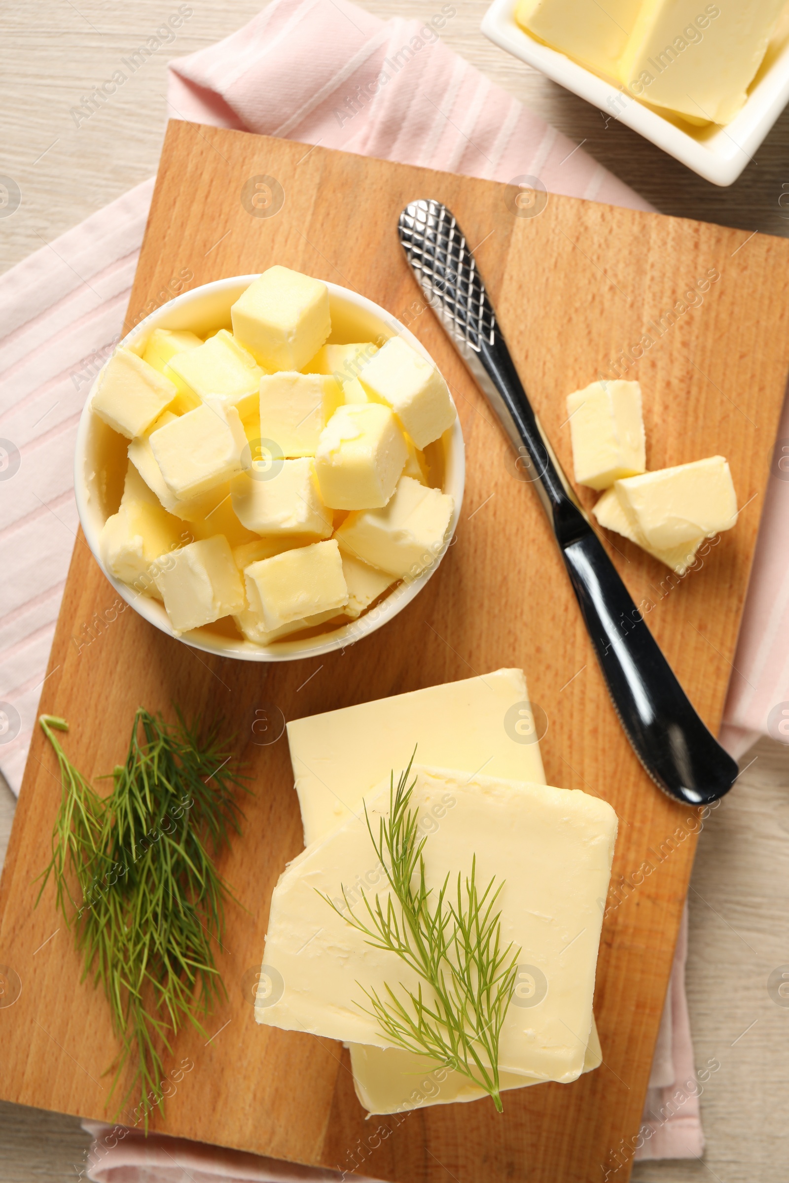 Photo of Tasty butter with dill and knife on wooden table, top view