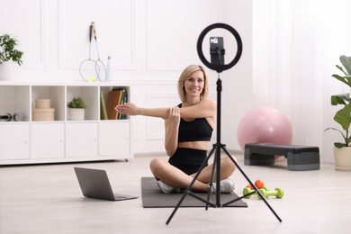 Smiling sports blogger streaming online fitness lesson at home