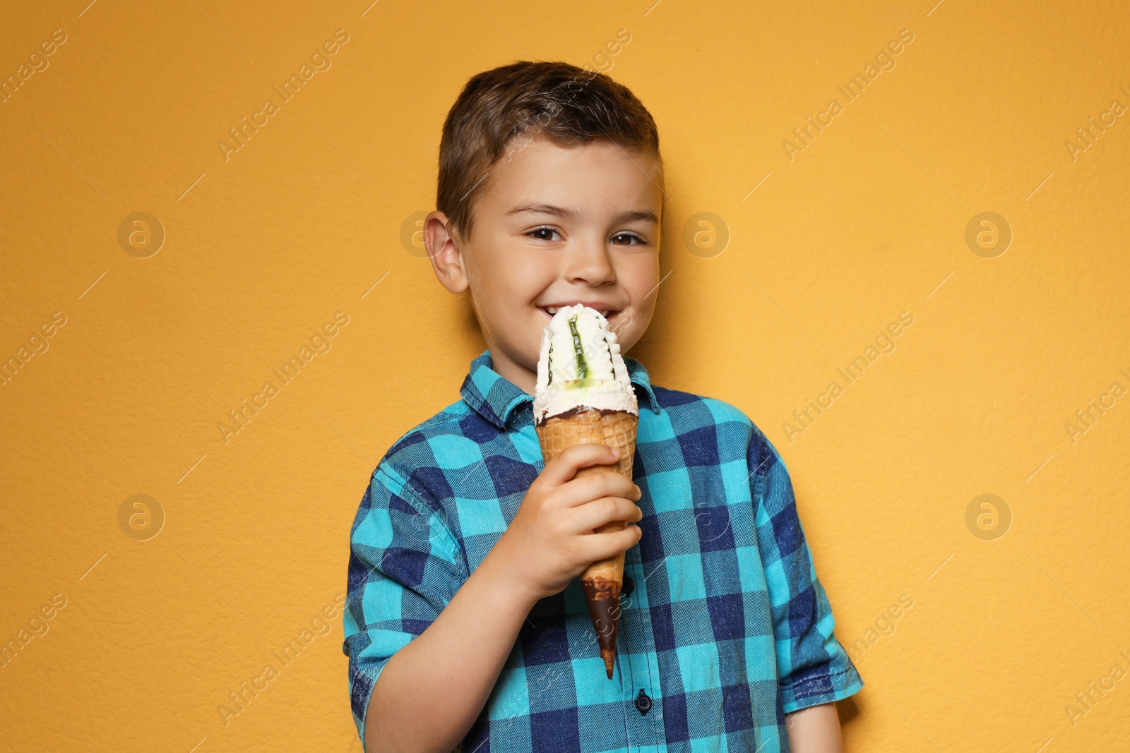 Photo of Adorable little boy with delicious ice cream against color background