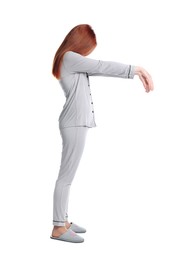 Young woman wearing pajamas and slippers in sleepwalking state on white background