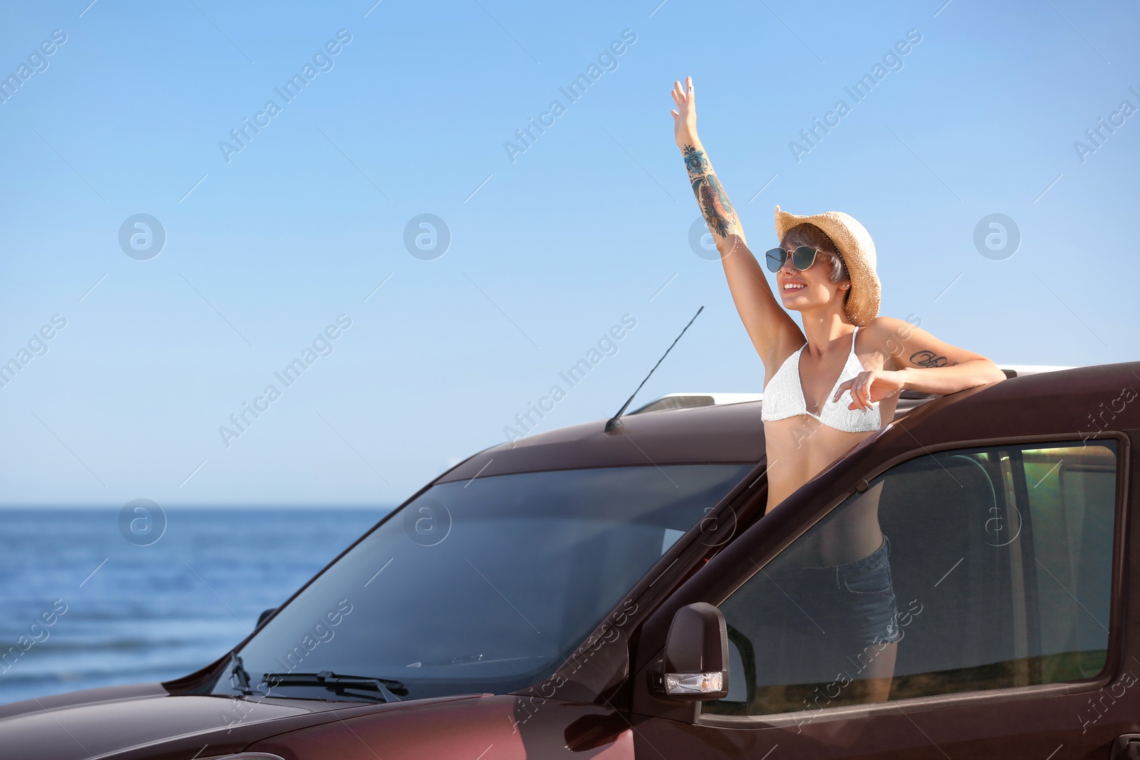 Photo of Young woman in straw hat near car on beach