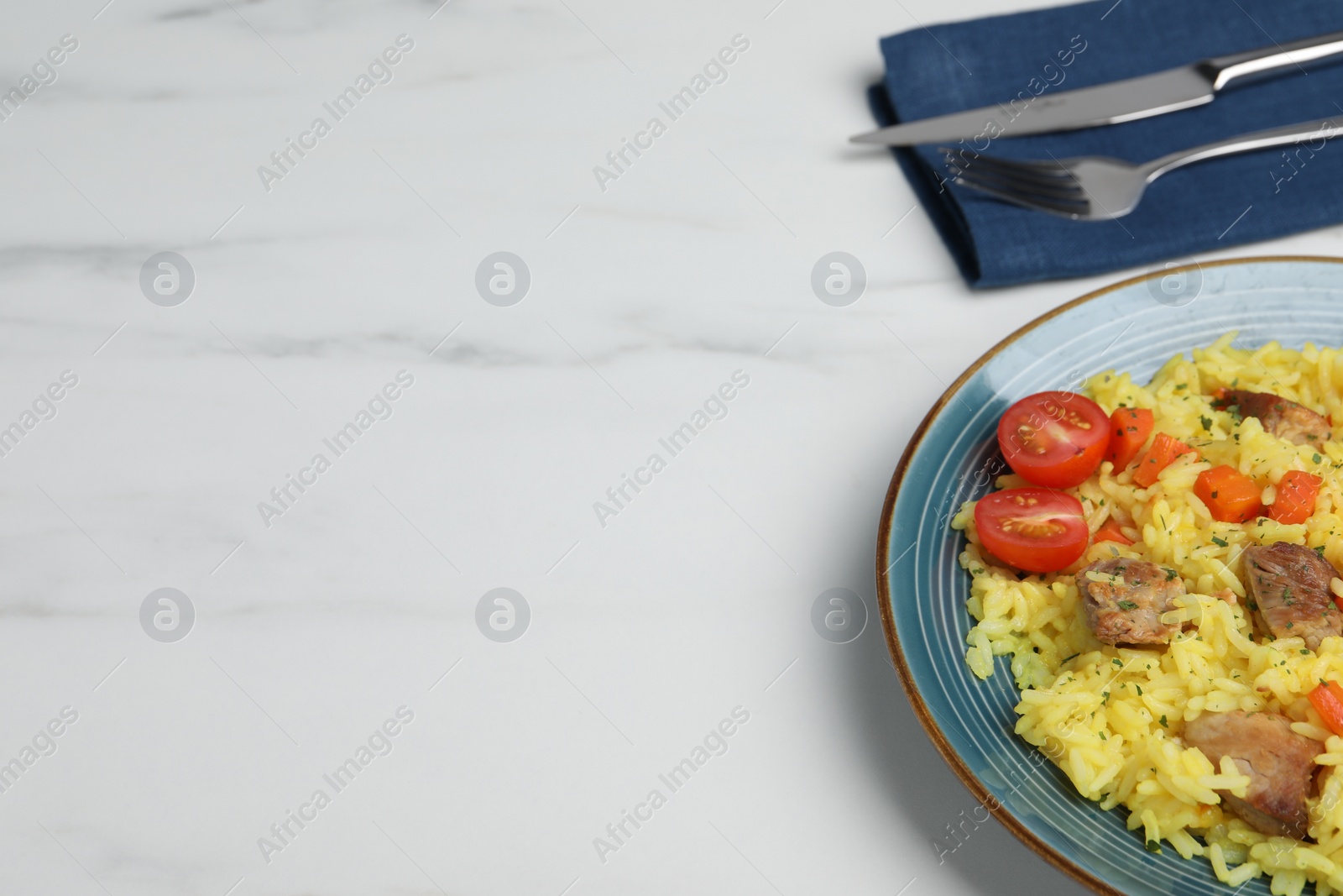 Photo of Delicious pilaf with meat served on white marble table, space for text