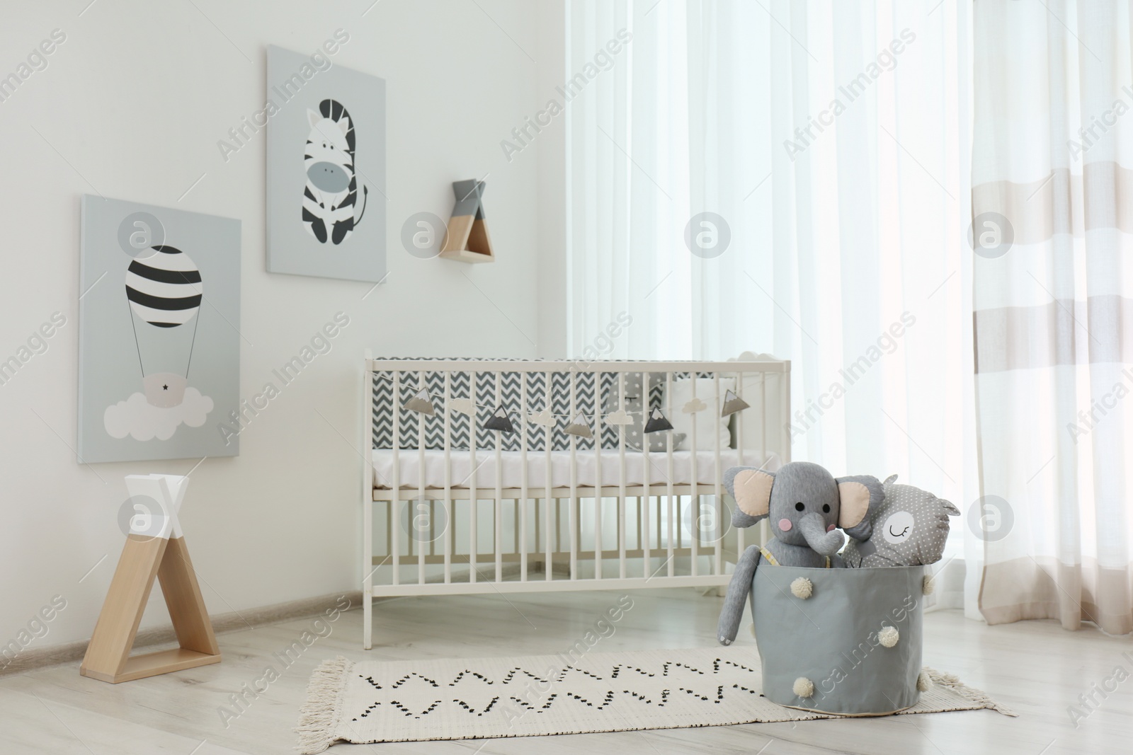 Photo of Stylish baby room interior with crib and cute pictures on wall