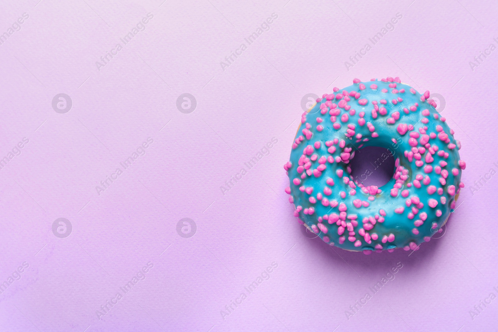 Photo of Delicious glazed doughnut with sprinkles on color background, top view