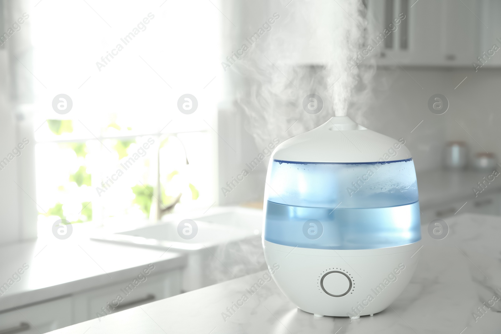 Photo of Modern air humidifier on table in kitchen. Space for text