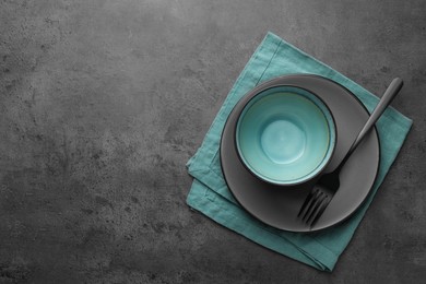Photo of Stylish empty dishware and fork on grey table, top view. Space for text