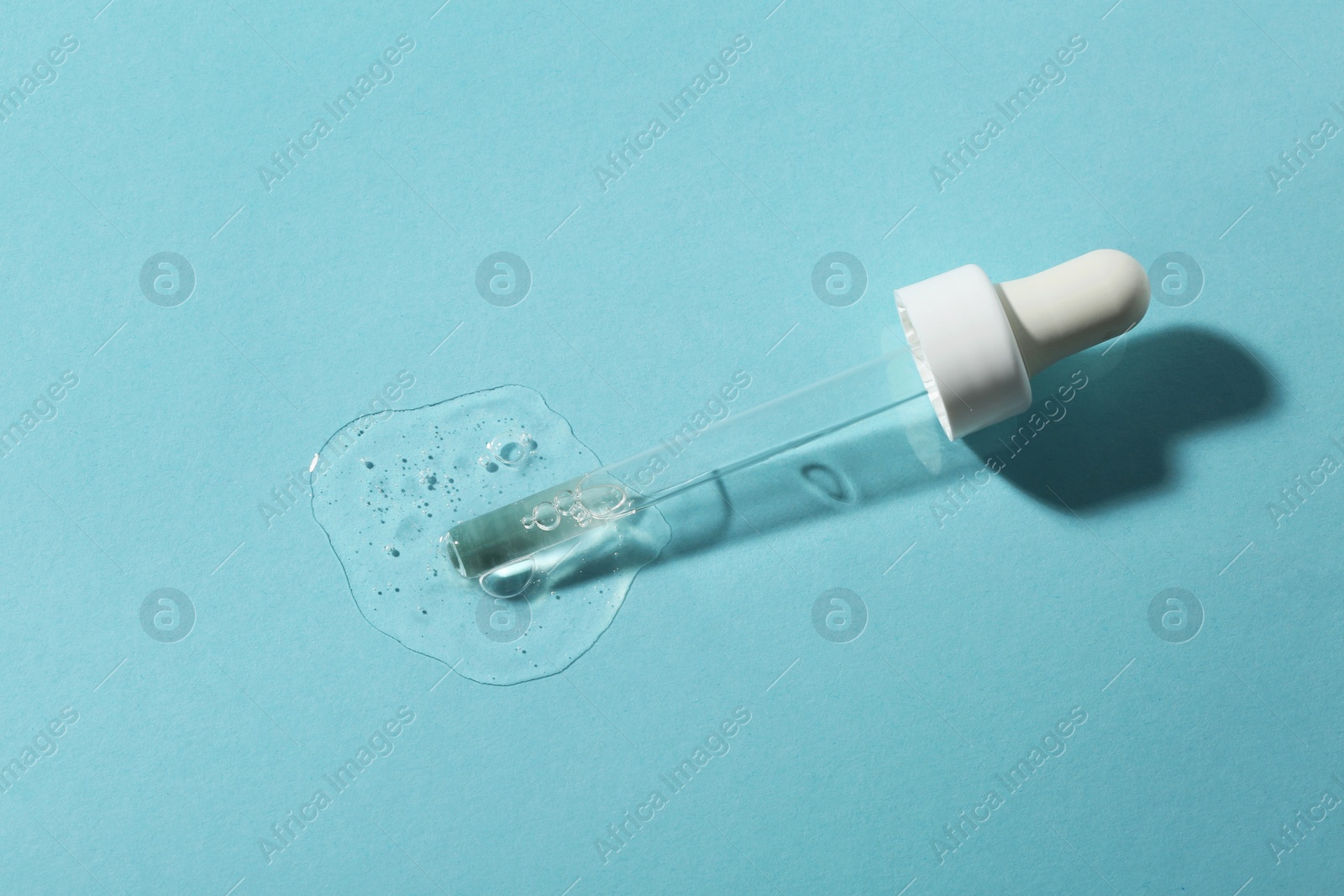 Photo of Pipette with cosmetic serum on light blue background, top view