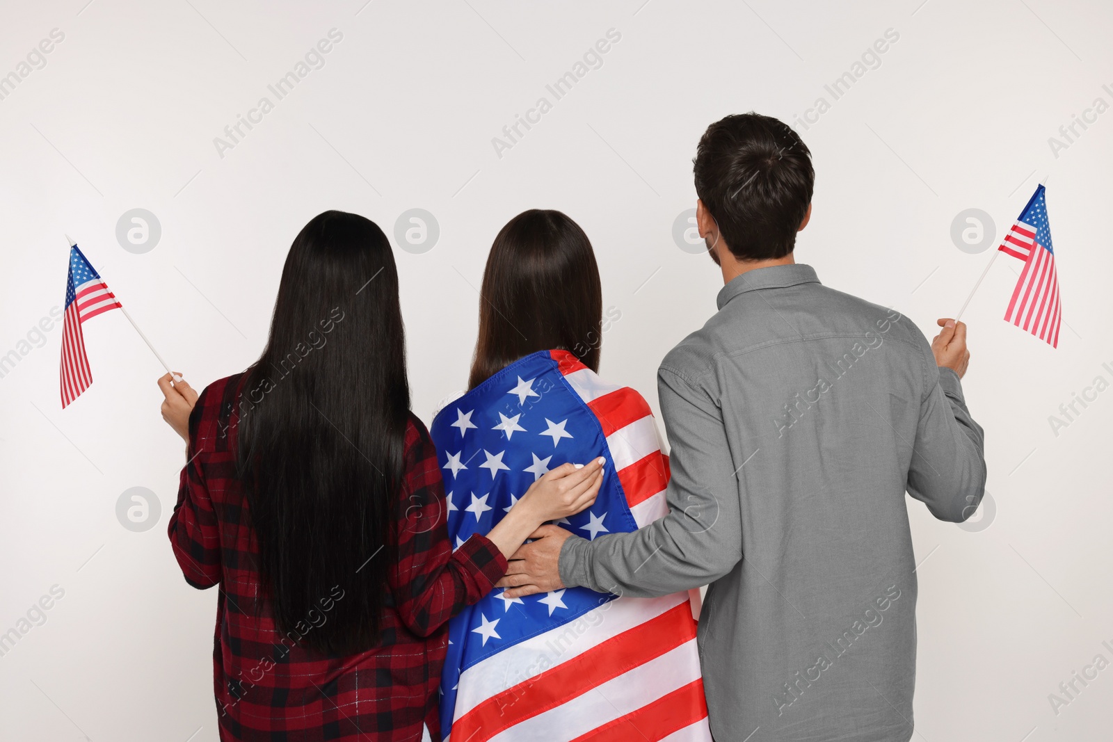 Photo of 4th of July - Independence Day of USA. Family with American flags on white background, back view