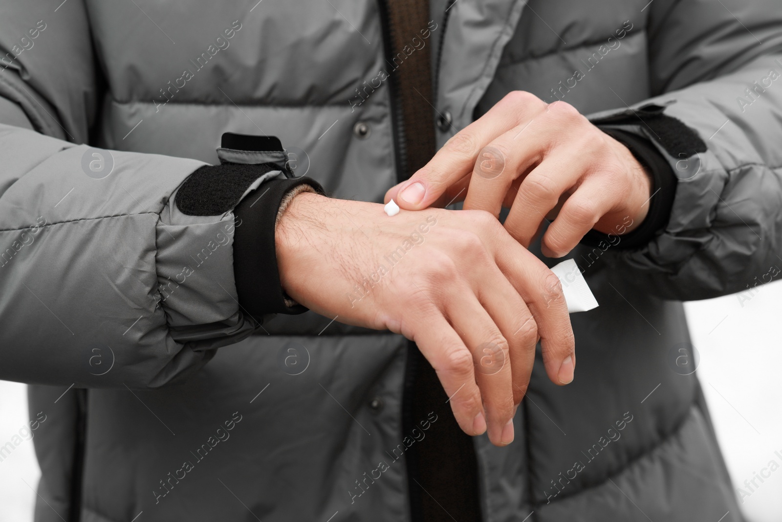 Photo of Man applying cream from tube onto hand, closeup. Winter care