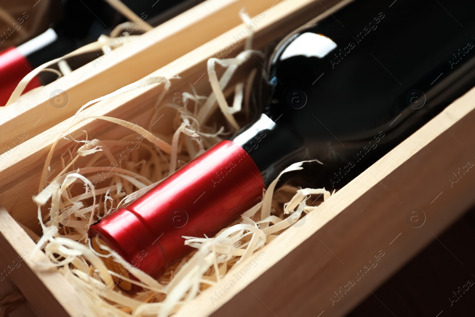 Photo of Bottles with delicious red wine in wooden boxes, closeup