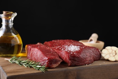 Photo of Fresh raw beef cuts with oil and spices on wooden board