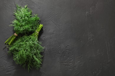 Photo of Bunches of fresh dill on grey textured table, top view. Space for text