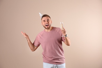 Photo of Portrait of happy man with party cap and champagne in glass on color background