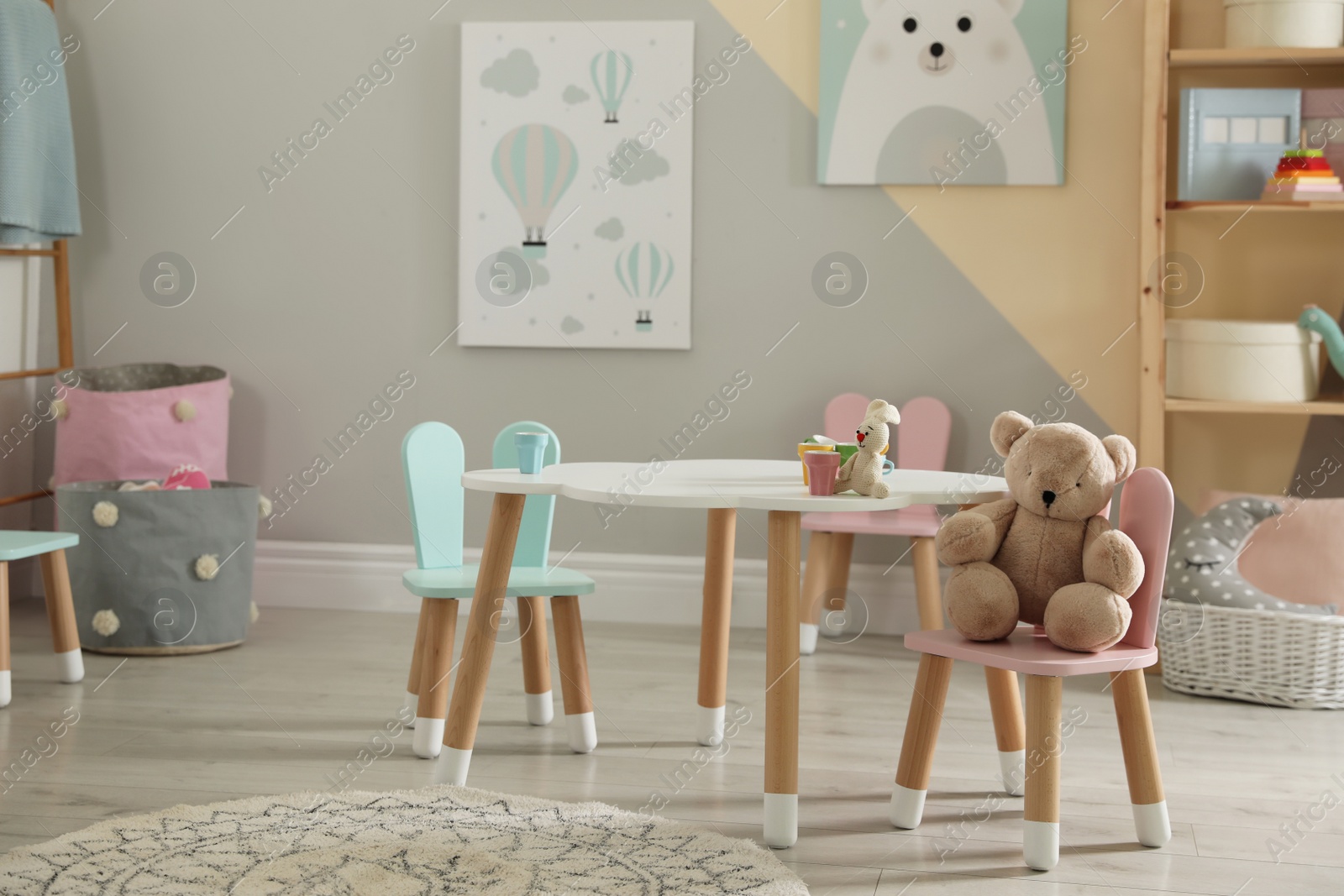 Photo of Small table and chairs with bunny ears in children's room interior