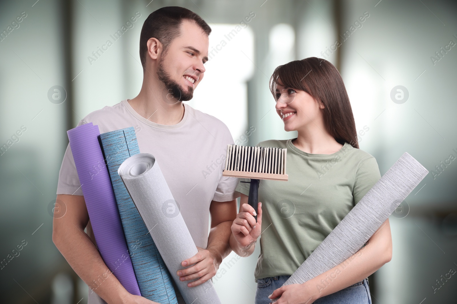 Image of Couple with wallpaper rolls and brush on blurred background