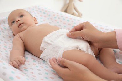 Photo of Mother changing her baby's diaper on table at home