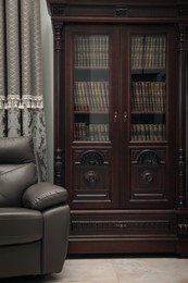 Photo of Comfortable armchair near wooden bookcase in library