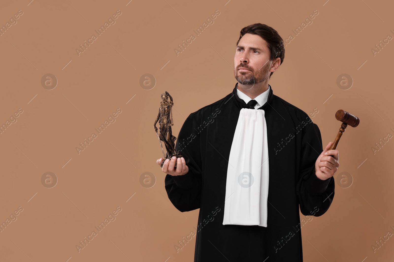 Photo of Judge with gavel and figure of Lady Justice on light brown background. Space for text