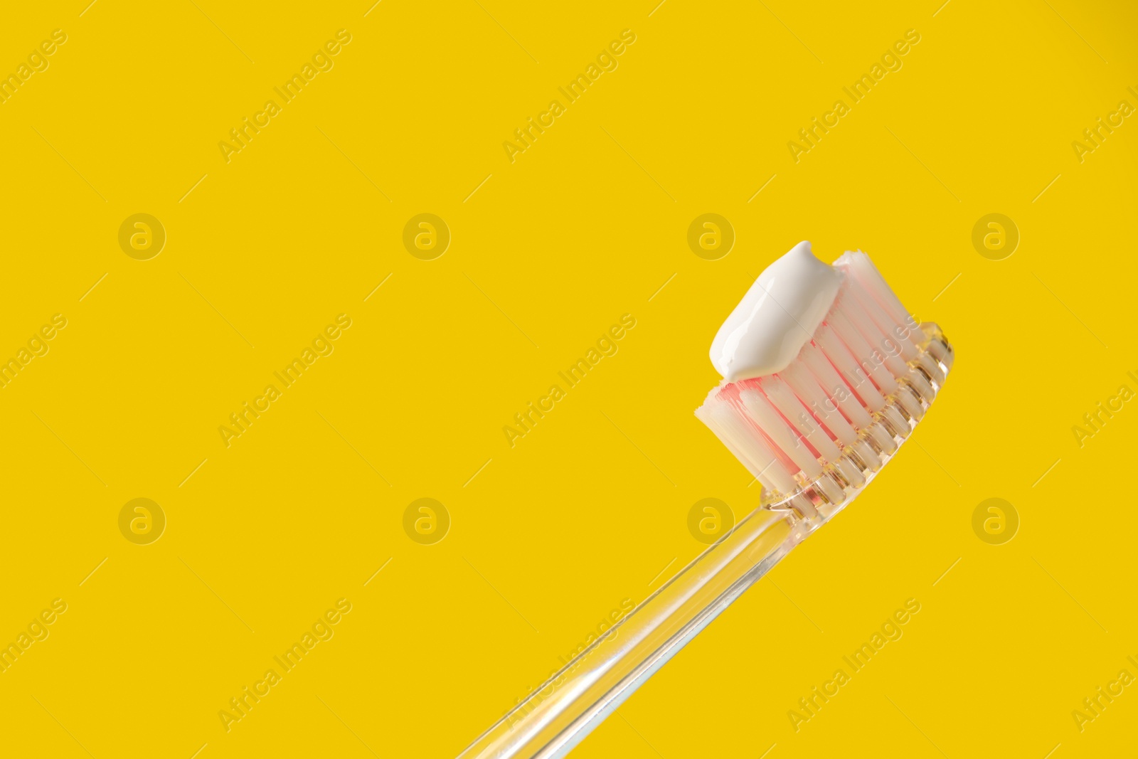 Photo of Brush with toothpaste on yellow background, closeup. Space for text