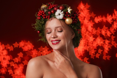 Photo of Beautiful young woman wearing Christmas wreath on blurred background. Bokeh effect