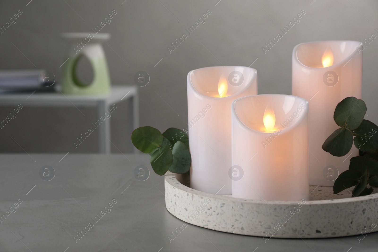 Photo of Decorative LED candles and eucalyptus on grey table, space for text