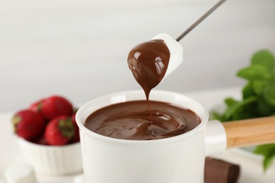 Photo of Fondue pot with chocolate and marshmallow against light background, closeup