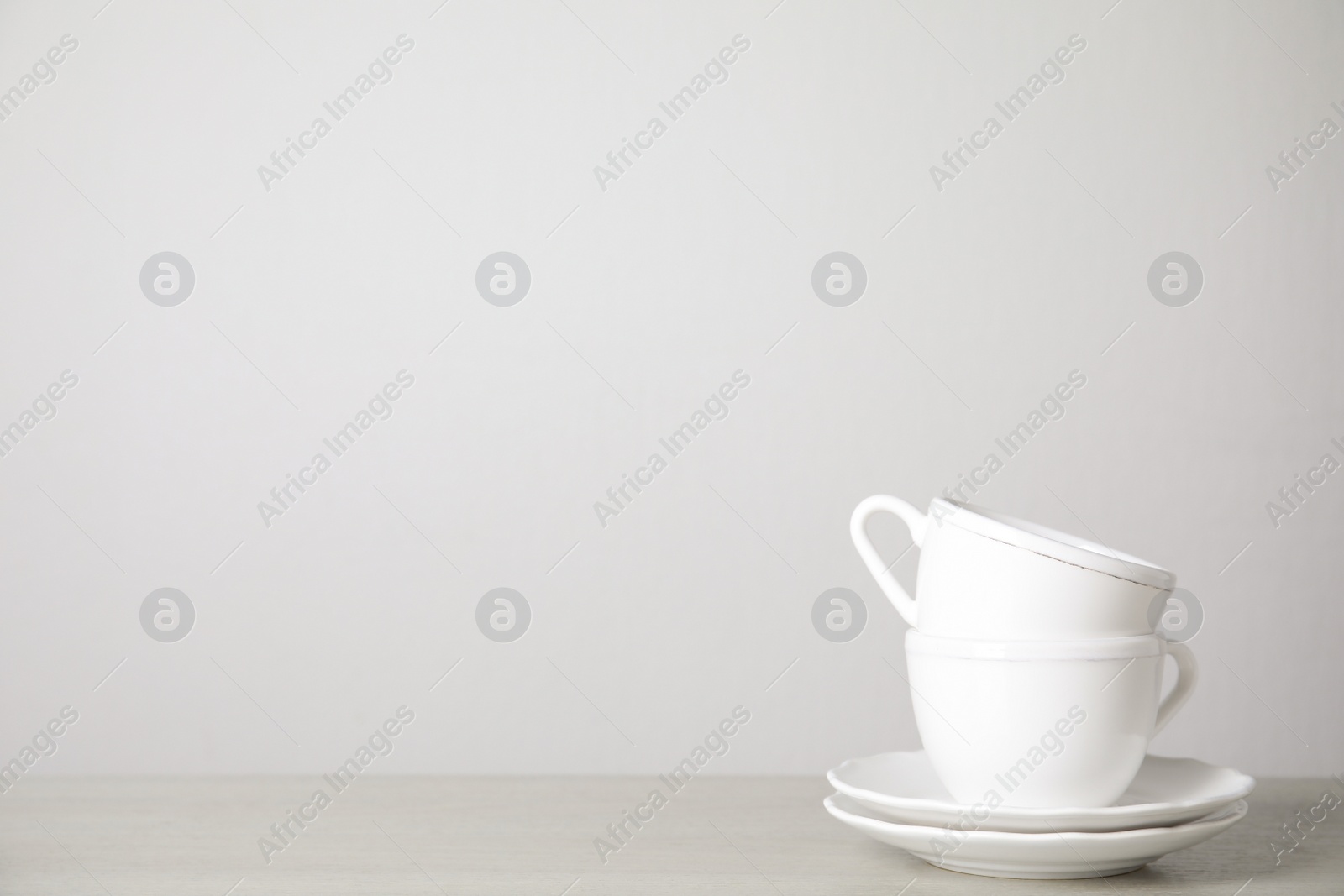 Photo of Ceramic saucers and cups on table against white background. Space for text