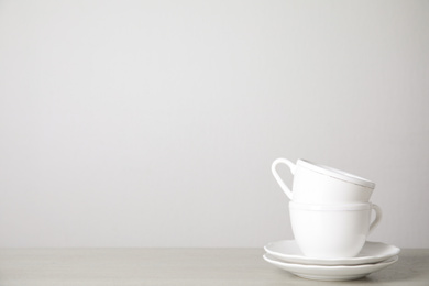 Photo of Ceramic saucers and cups on table against white background. Space for text