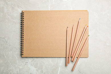 Photo of Stylish notebook and pencils on marble table, top view