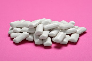 Photo of Tasty white chewing gums on pink background