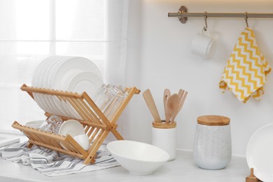 Drying rack with clean dishes on countertop in kitchen