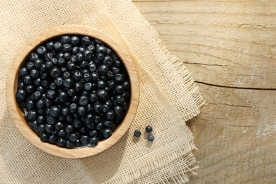 Bowl of delicious bilberries on wooden table, top view. Space for text