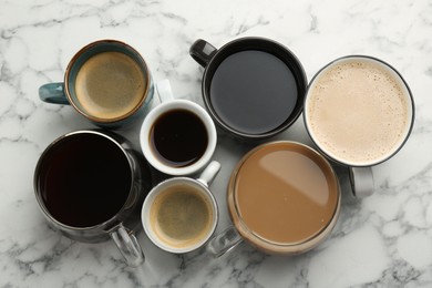 Photo of Different coffee drinks in cups on white marble table, flat lay