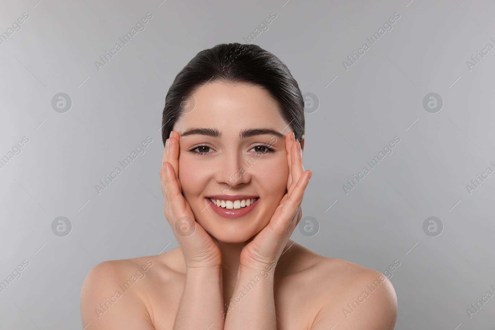 Photo of Young woman massaging her face on grey background