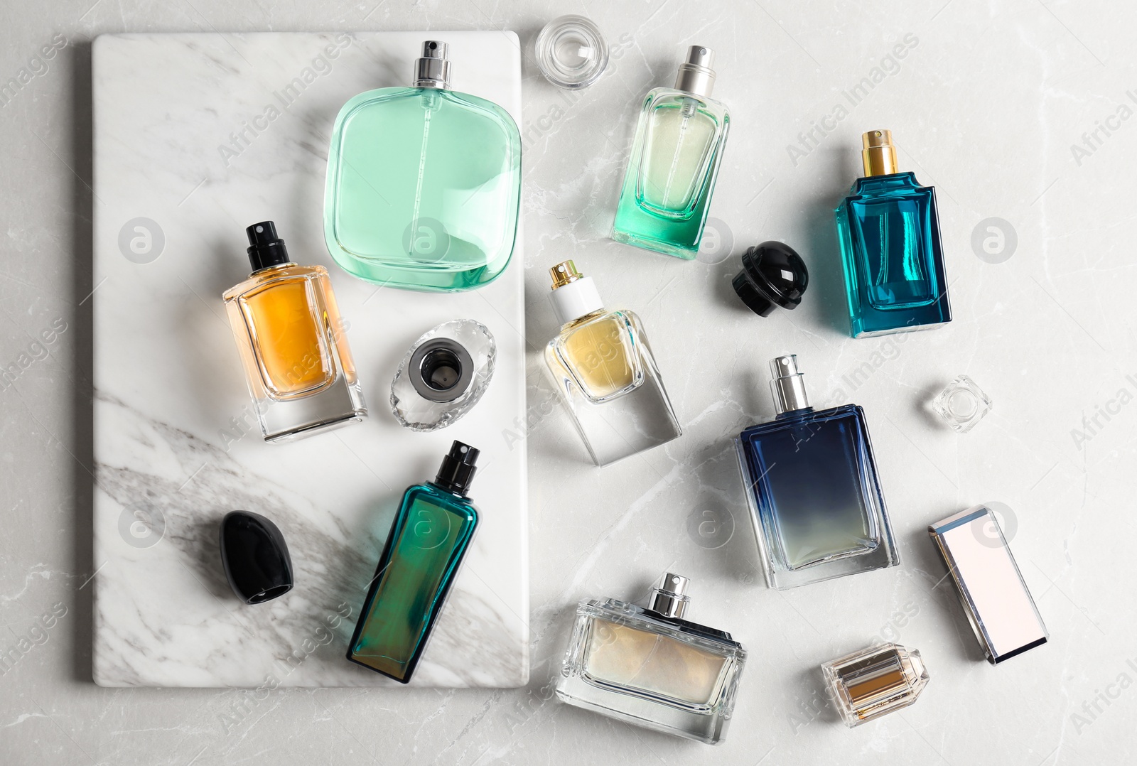 Photo of Perfume bottles on light background, flat lay